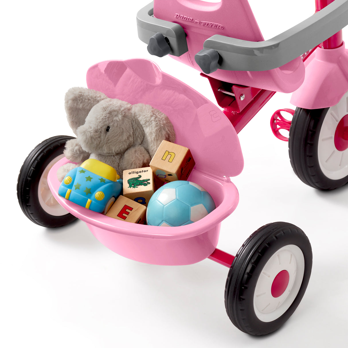 Pink tricycle with toys in the rear basket on a white background