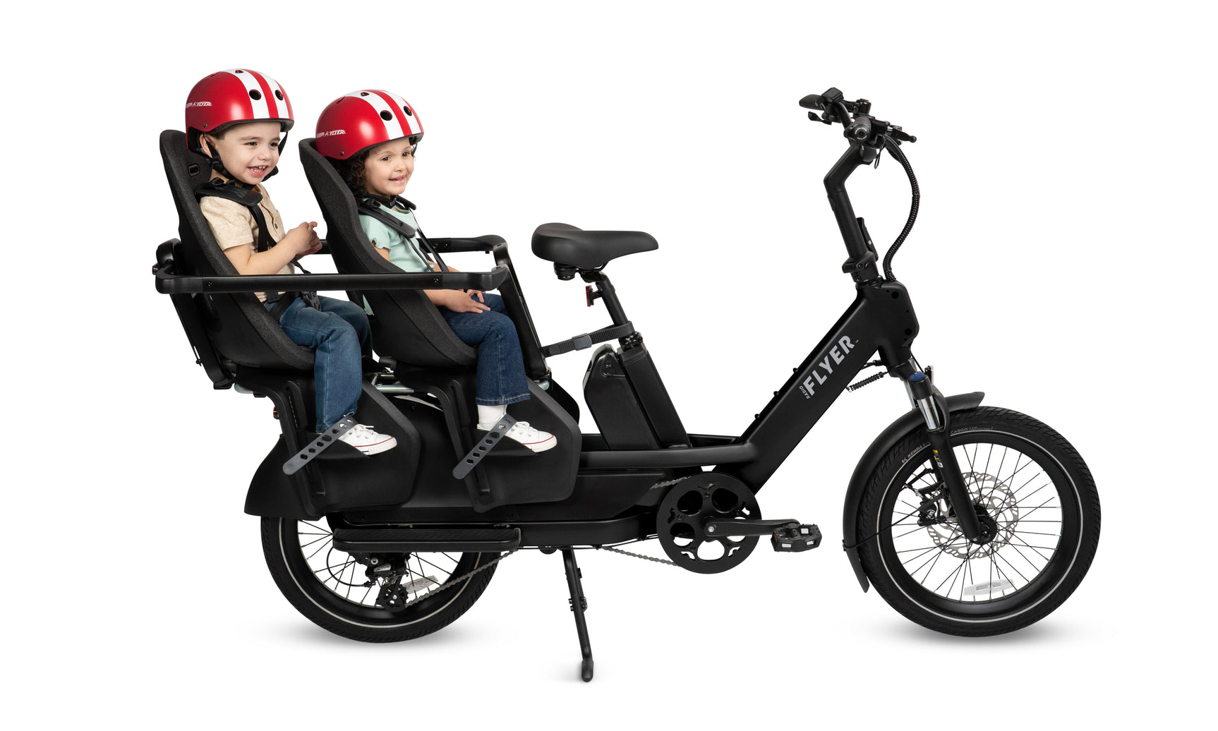 Two children sitting in two Thule Yepp Maxi seats in the kid hoop accessory on a black electric bike with helmets on a white background
