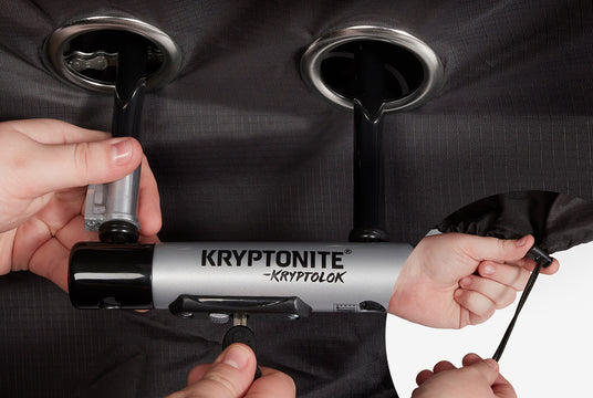 Person using a Kryptonite lock on an eBike that has a bicycle cover on it.