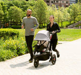Grown-ups jogging with child in Momentum Jogging Stroller