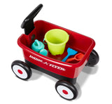 child using toy wagon as pull wagon with garden tools inside