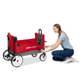 A woman kneels beside a red and gray Radio Flyer wagon, unzipping the side wall. The wagon has white wheels with black tires and a black handle, shown on a clean white background.