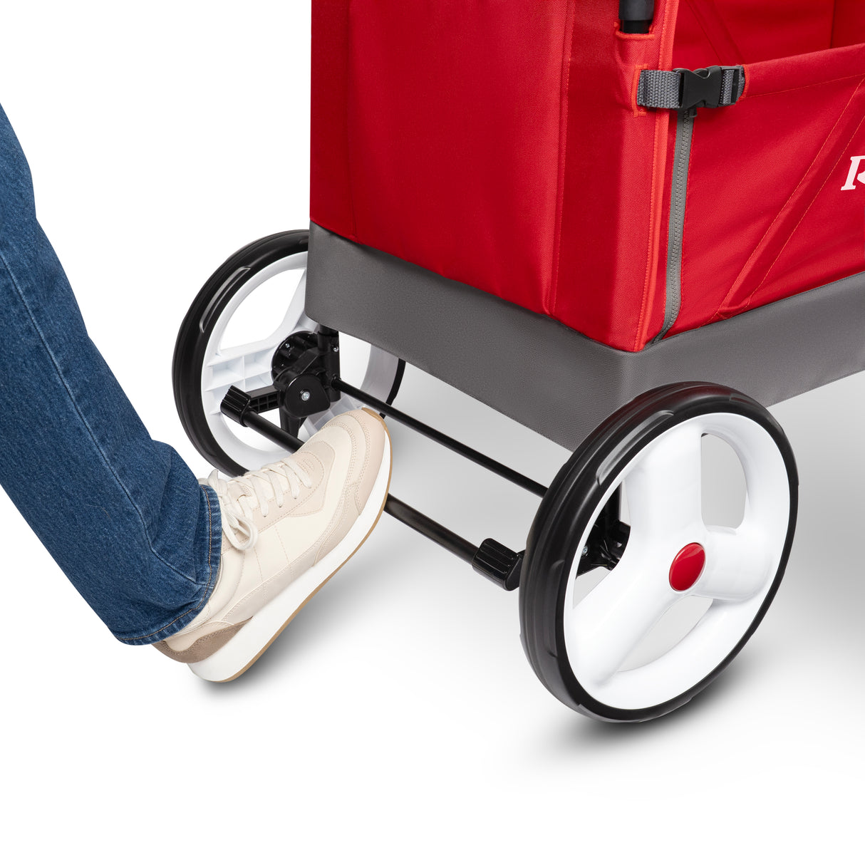 A close-up of the back of a red wagon with a woman's foot pressing down on the rear foot brake