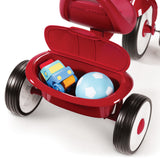 Red tricycle with a rear storage bin opened containing toys on a white background