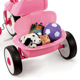 Rear storage bin on a pink tricycle with the lid open showing toys inside on a white background