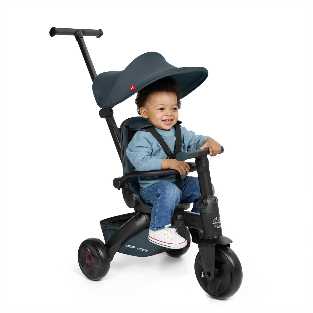 Child sitting in a black and steel blue stroller tricycle on a white background