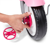 Hand adjusting a pink wheel on a toy tricycle against a white background