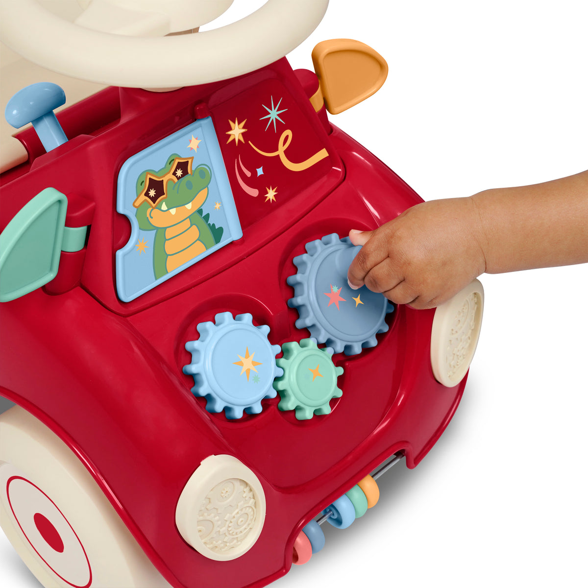 A close-up of a child's hand twisting the blue gears on the hood of the red Radio Flyer ride-on push car