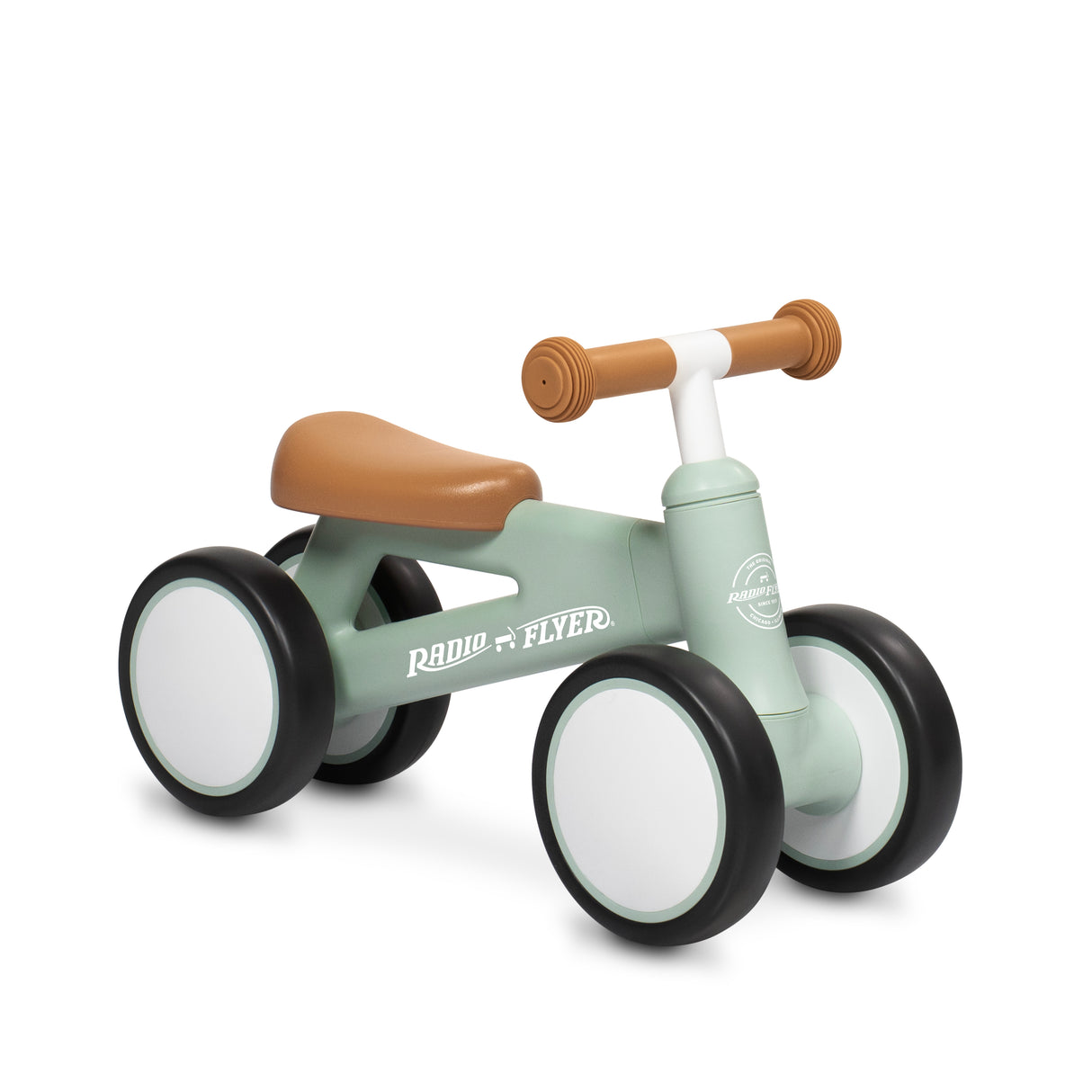 A Radio Flyer balance bike with a sage green frame, brown seat and handlebar grips, and white wheels with black tires, shown on a white background.