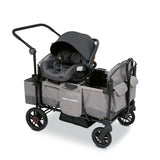 Gray stroller wagon with a car seat resting on the car seat adapter on the side walls of the wagon